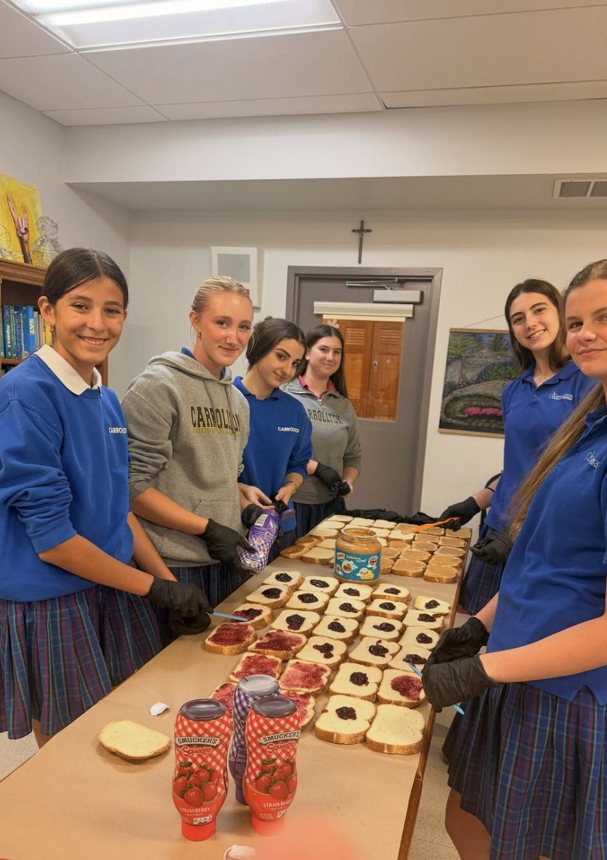 Students smiling over a table of fresh sandwiches