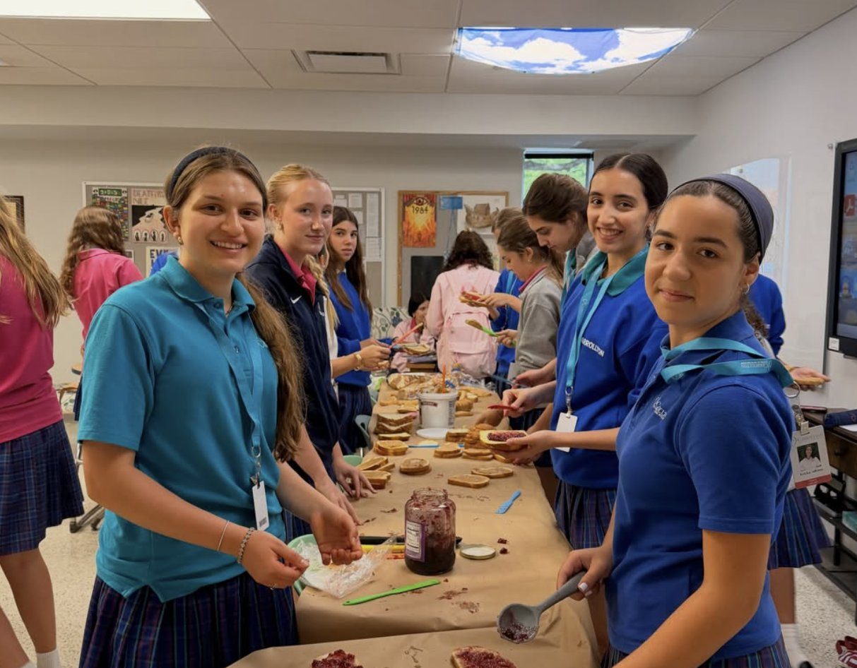 Students spreading jelly on bread at a long table