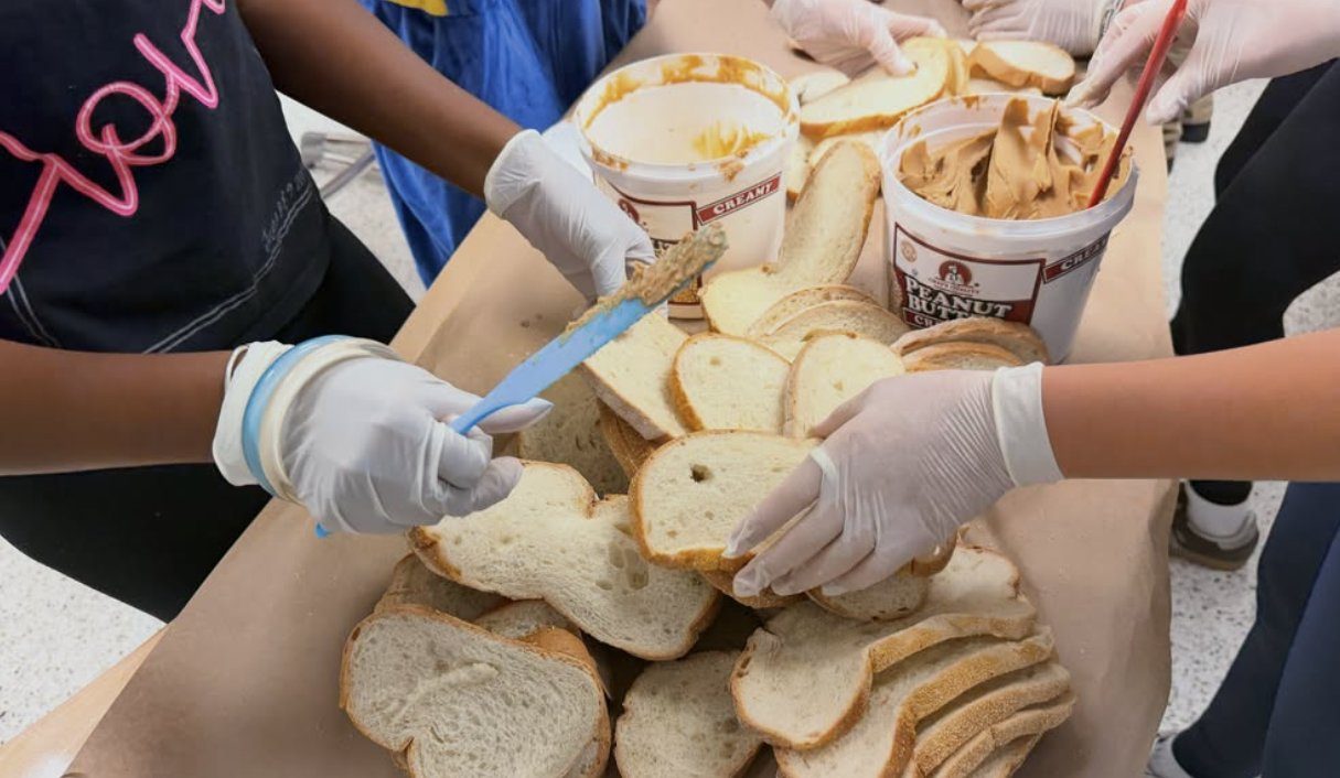 Gloved hands spreading peanut butter on bread